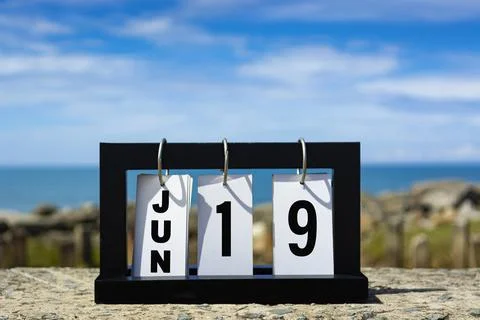 Jun 19 calendar date text on wooden frame with blurred background of ocean. Stock Photos