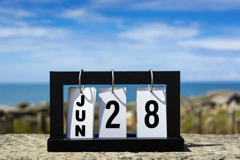 Jun 28 calendar date text on wooden frame with blurred background of ocean. Stock Photos