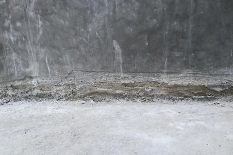 Junction between a polished dark gray concrete wall and a rough unfinished .. Stock Photos