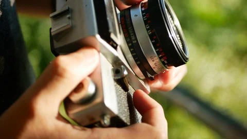 A jung man preparing a retro 35 mm camera to take a photo in the green natur. 4k Stock Footage 119725178