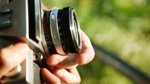 A jung man preparing a retro 35 mm camera to take a photo by the lake. 4k 動画素材 119725883