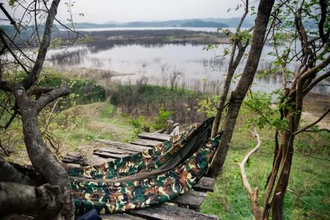 A jungle hammock hangs between trees on the wooden scaffold platform Stock Photos
