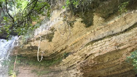 Jungle Waterfall Cascading Over Layered Rock Face, Panning Left Video stock 325646452