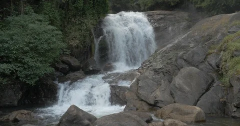 A jungle waterfall flows over large boulders Stock Footage 120054596