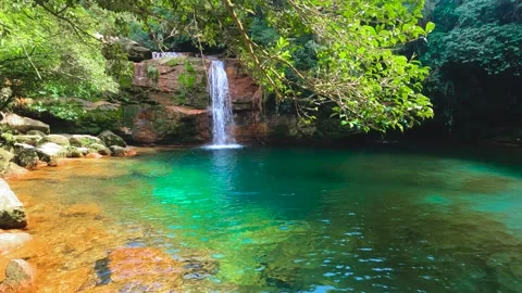 Jungle waterfall with white waters running down Rocky ridge of hill to blue.. Stock Footage 271171082