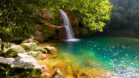 Jungle waterfall with white waters running down Rocky ridge of hill to blue.. Stock-Footage 271171788