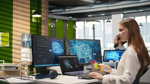 Junior dev in office relies on AI tech to run tasks across multiple devices Stock Photos