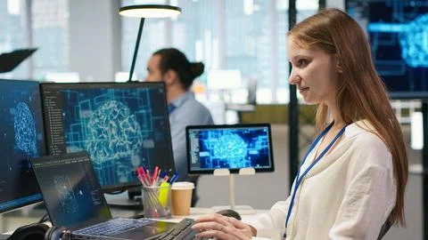 Junior dev in office relies on AI tech to run tasks across multiple devices Stock Photos