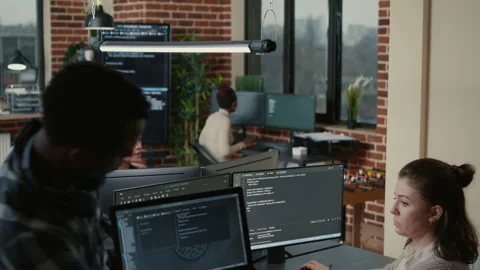 Junior developer sitting down on desk showing laptop with source code to senior Stock Footage 168239518