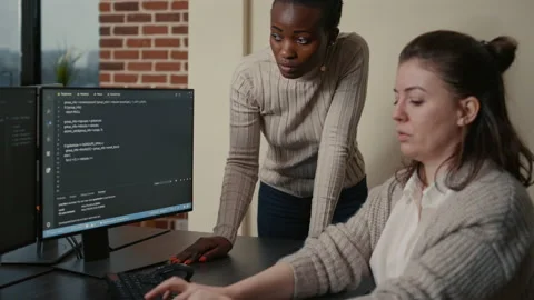 Junior developer writing source code under senior dev supervision sitting at Stock Footage 168239877