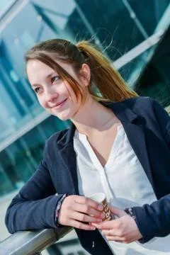 Junior executive having a coffee break in front of her company Stock-Fotos
