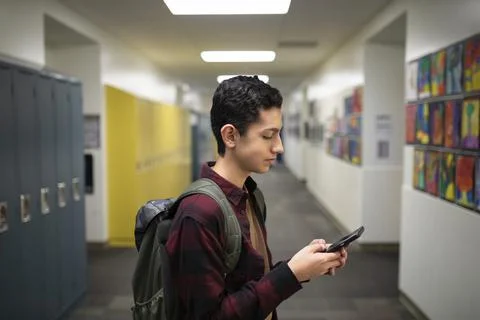 Junior high boy student using smart phone in corridor Stock Photos