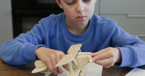 Junior schoolboy attaches propeller and plays with wood airplane Stockbeeldmateriaal 323974000