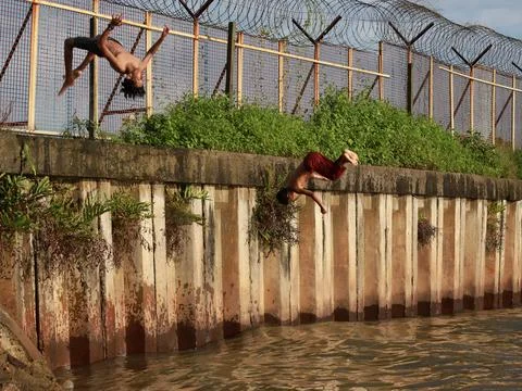 Junior schoolboy performed back-flip from pier into azure sea Stock Photos