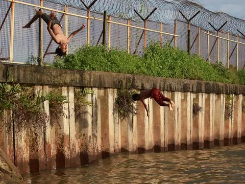 Junior schoolboy performed back-flip from pier into azure sea Stock Photos