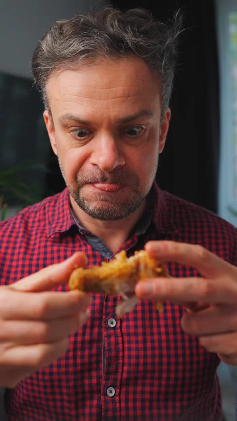 Junk food advertisement concept. Man eating fried chicken, enjoying fast food. Stockbeeldmateriaal 342958143