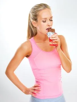 Just a bit is ok...fit young woman in exercise clothes eating a chocolate bar. Stock Photos