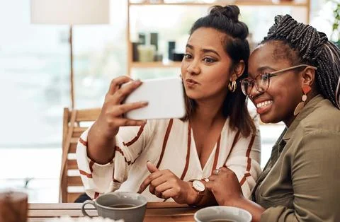 Just call us the selfie queens. Shot of two young women taking selfies at cafe. Stock Photos