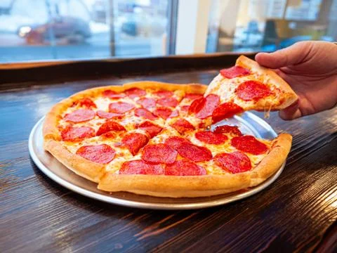 Just cooked Pizza pepperoni on a table in a cafe in front of a window with a Stock-Fotos