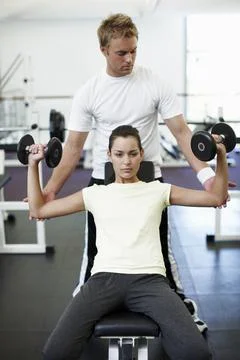 Just a couple more. an attractive young woman weight training with her personal Stock Photos