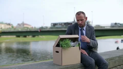 Just fired, unemployed sad young businessman sitting in the city Stock Footage