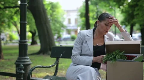 Just fired, unemployed sad young businesswoman talking on cellphone in the park Stock Footage