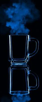 Just a glass on a black background with a reflection. Blue color, with steam. Stock Photos