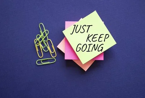 Just keep going symbol. Yellow steaky note with paper clips with words Just.. Stock Photos