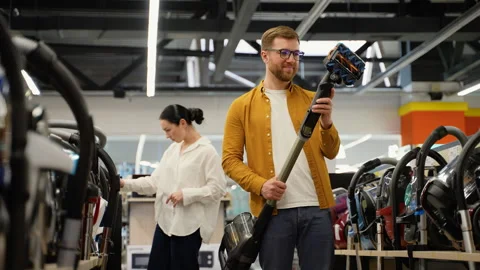 Just married couple choosing vacuum cleaner in an electronics store for new home Stock Footage 279638997