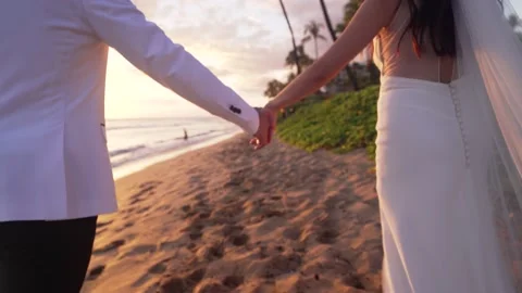 Just married couple walk down tropical beach during golden hour in Maui Hawaii. Stock Footage 134527253