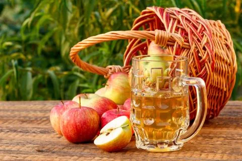 Just picked apples in a wicker basket and apple cider in glass goblet Stock Photos