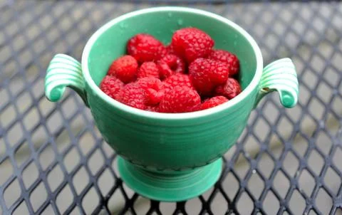 Just picked berries of raspberry in ancient cup lost in garden in the rain Stock Photos