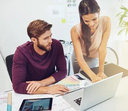 Just a quick question. two young architects working on a laptop. Stock Photos