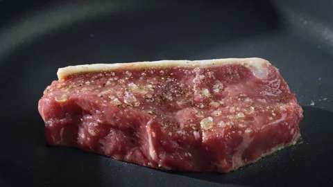 Just a raw piece of beef steak fried on a hot, black pan. Food preparation. Stock Footage 277452723