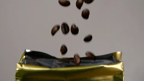 Just roasted coffee beans are poured down to the packaging in slow motion Stock Footage 113594880