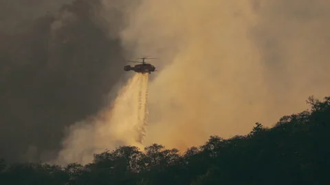KA-32 Fire fighting helicopter dropping water on forest fire Stock Footage