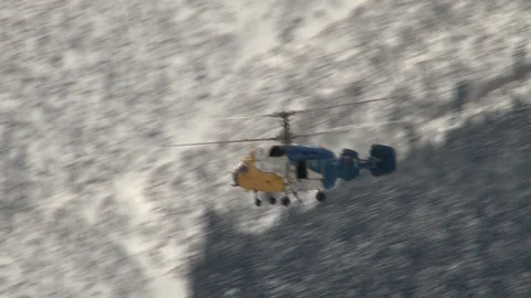 Ka-32 helicopter fly over snow-covered wooded mountains. Stock Footage 106607418