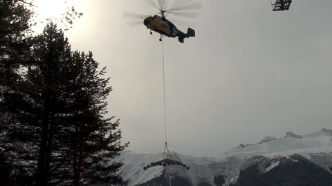 Ka-32 helicopter with load on external suspension atinstallation of of cableway Stock Footage 106771838
