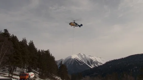 Ka-32 rises vertically with bunker on background of snow-capped peaks Stock Footage 106857199