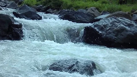 Kali Gelis River stream surging between large rocks because it is raining Stock Footage 124725844