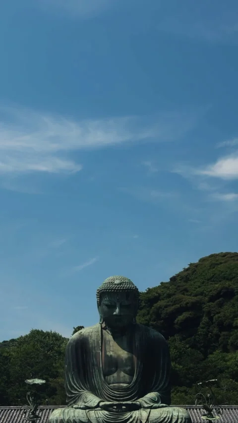Kamakura Daibutsu bronze statue with green trees and blue sky Stock Footage 345169680