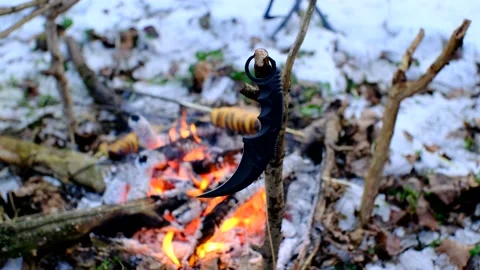 Karambit knife on the branch in front of bonfire in the dark snowy forest Stock Footage 167743484