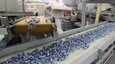 Karamel 059Wrapped caramel candies fall from above on a swaying conveyor belt Stock Footage 130395366