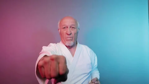 In karate, an elderly male athlete practices punches Stock Footage 340319190