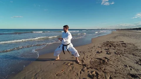 Karate fighter doing fast and powerful movements on the seashore at sunset on Video stock 146604927