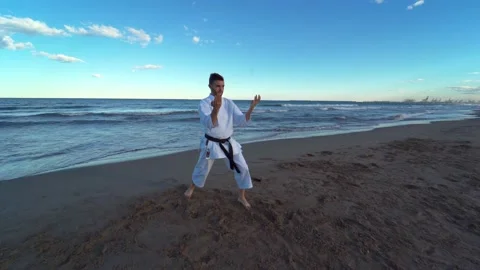 Karate fighter practicing a kata on the beach at sunset. Karate fighter pract Stock Footage 146604814