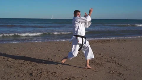 Karate fighter practicing kata on the beach at sunset and doing jumping, bala Stock Footage 146605010