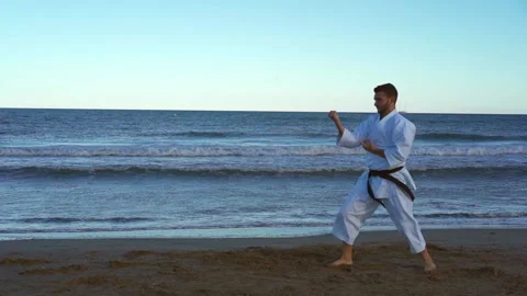 Karate fighter practicing katas on the beach at sunset and doing very powerfu Stock Footage 146604940