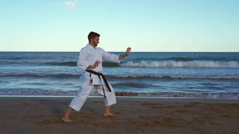 Karate fighter practicing katas on the beach at sunset and doing very energet Video stock 146604976