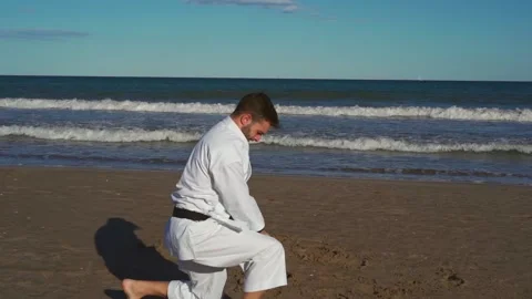 Karate fighter practicing katas on the beach at sunset. Karate fighter practi Stock Footage 146605011